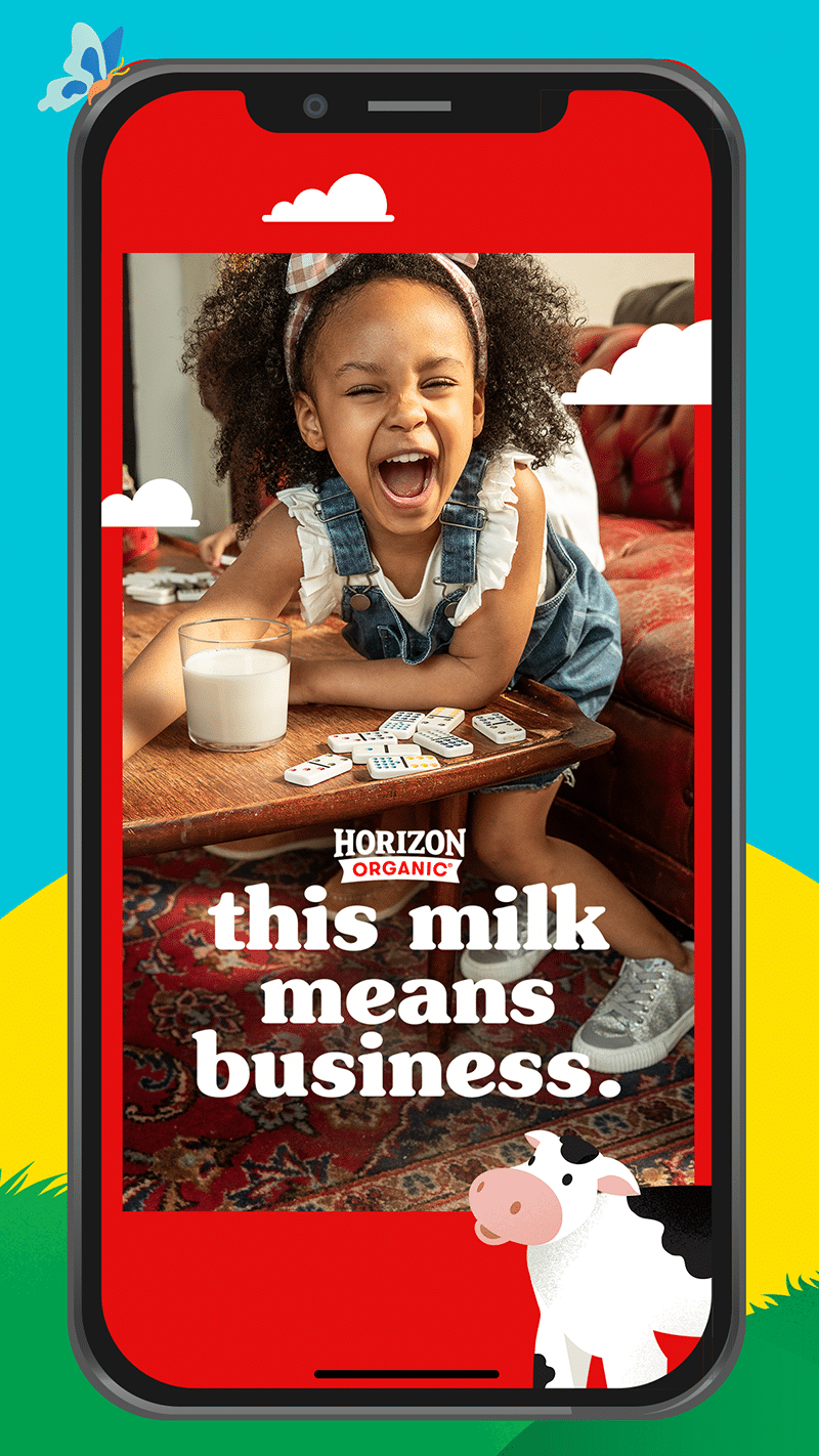 In the center, a still image of a young girl with curly brown hair in the middle of laughing. She is playing dominoes and has a glass of milk next to her. The headline over the image reads, “this milk means business.”