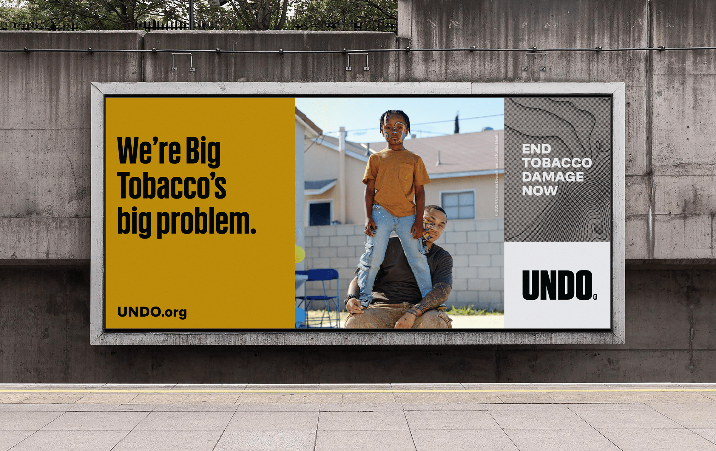 Isaiah and his 7-year-old son, Isaiah Jr. In their Compton backyard, the dad is sitting while Isaiah Jr. is standing on top of his dad’s lap in a powerful stance. Both father and son are gazing strongly at the camera. The headline reads “We’re Big Tobacco’s big problem.”