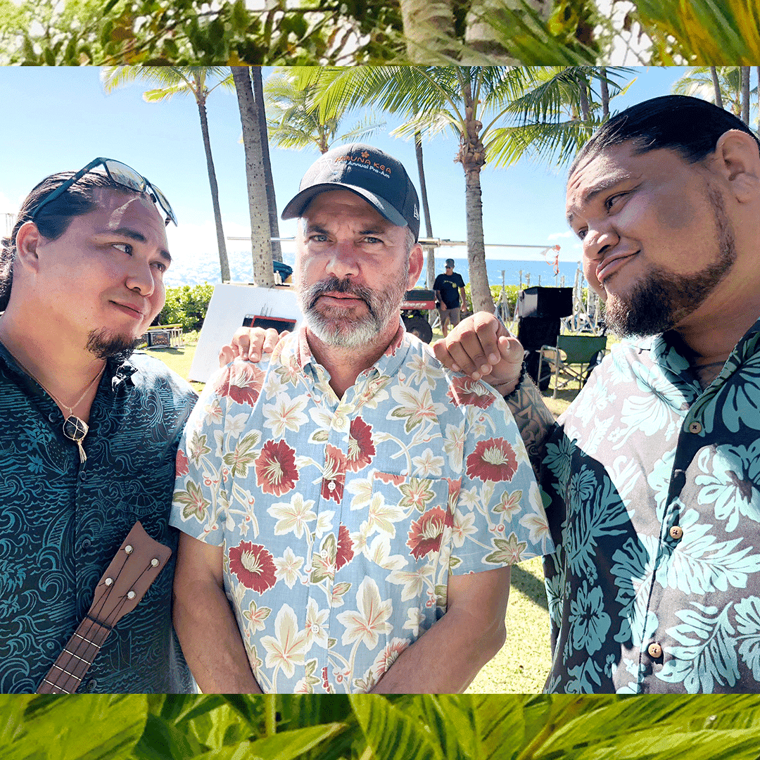 Parker in a floral shirt and baseball cap is flanked by Brutus and David in Hawaiian shirts, one holding a ukulele.